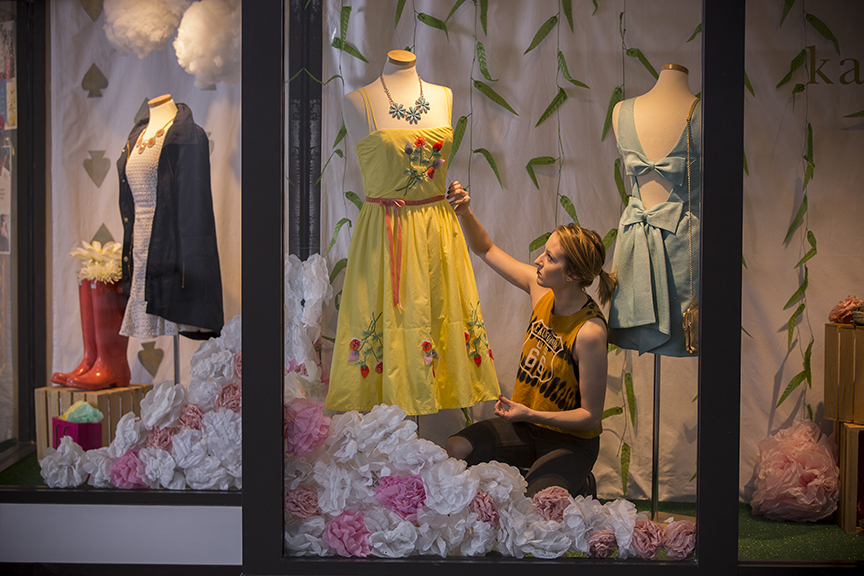 young woman adjusting dress in a window display