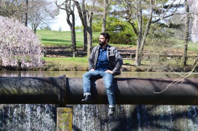 Paolo Scardina, an assistant professor of practice in the Charles E. Via Jr. Department of Civil and Environmental Engineering, sits on a sewer pipe at the spillway of the Virginia Tech Duck Pond.