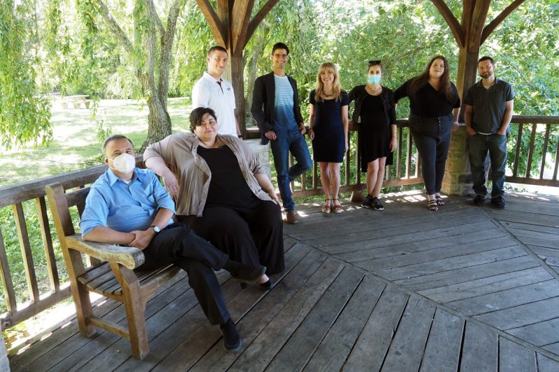 Group photo of eight members of the SPECTRA editorial team in a gazebo surrounded by greenery and trees.