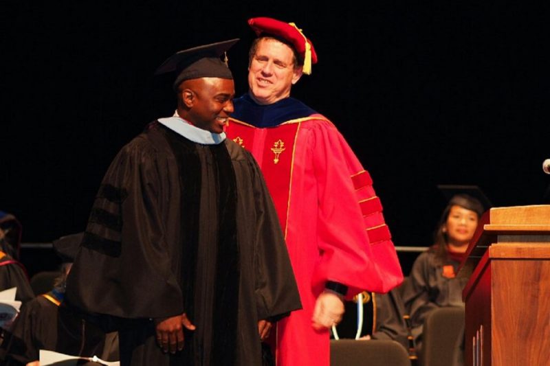 William “Bill” Glenn hoods a graduate student during Commencement.