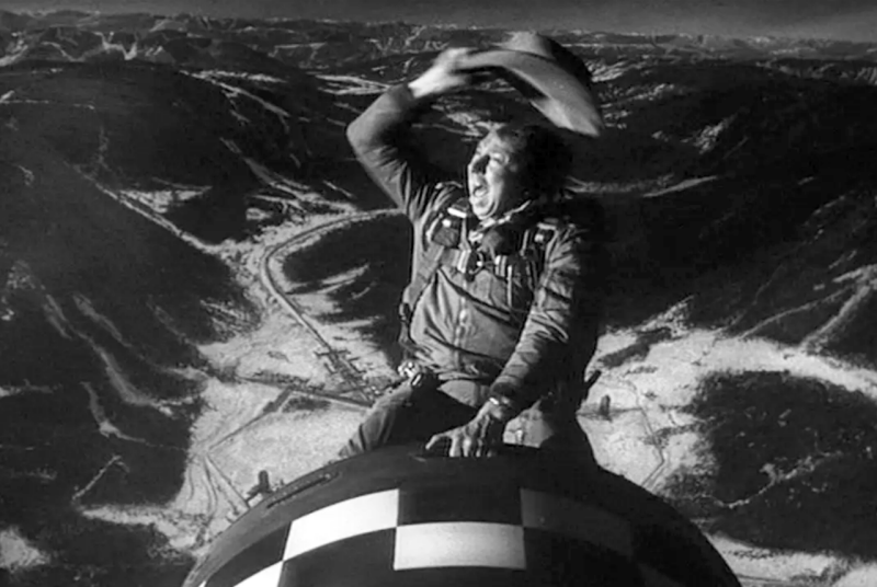 A man riding a bomb like a horse, waving his hat above his head