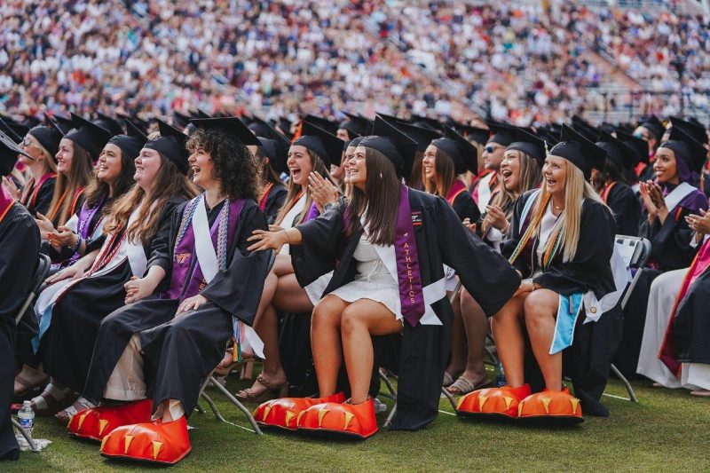 Rachel Mirsen, Masan Brown, and Abby Stewart react as they are "revealed" at the 2023 commencement as students who portrayed the HokieBird during their time at Virginia Tech. 