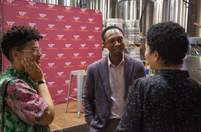 Sylvester Johnson speaking with two alumni inside a brewery