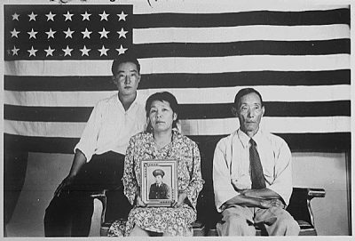 The Hirano family, George (left), Hisa (center) and Yasbei with picture of a United States serviceman at the Colorado River Relocation Center in Poston, Arizona. National Archives.