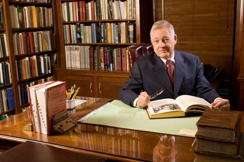 A portrait of Bud Robertson in his office, sitting behind his desk.