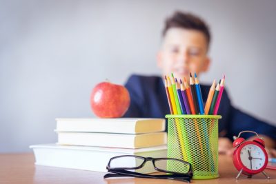 Male young student with books, pencils, and apple.