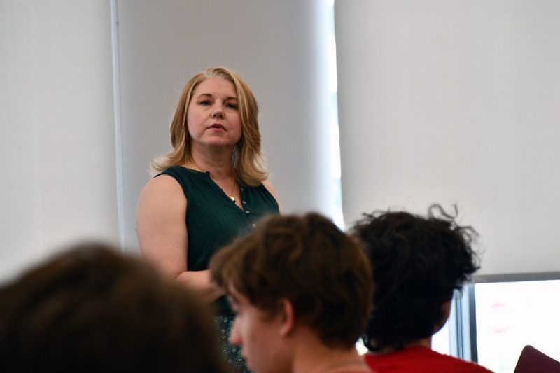 Woman stands in front of classroom.