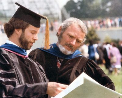 Two male faculty wearing regalia during commencement.