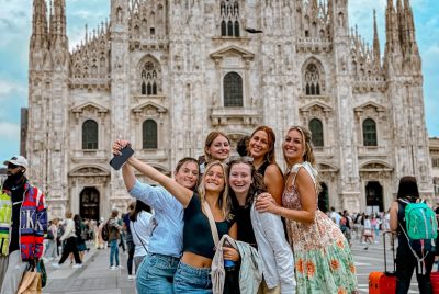 A group of college students smile in front of a castle in Milan, Italy.