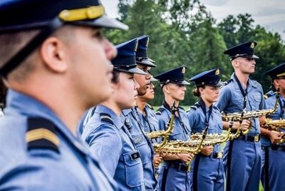 Members of the Highty-Tighties band stand in their blue uniforms, holding saxophones.