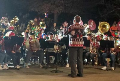Low brass players play outdoors during a TubaChristmas holiday event.