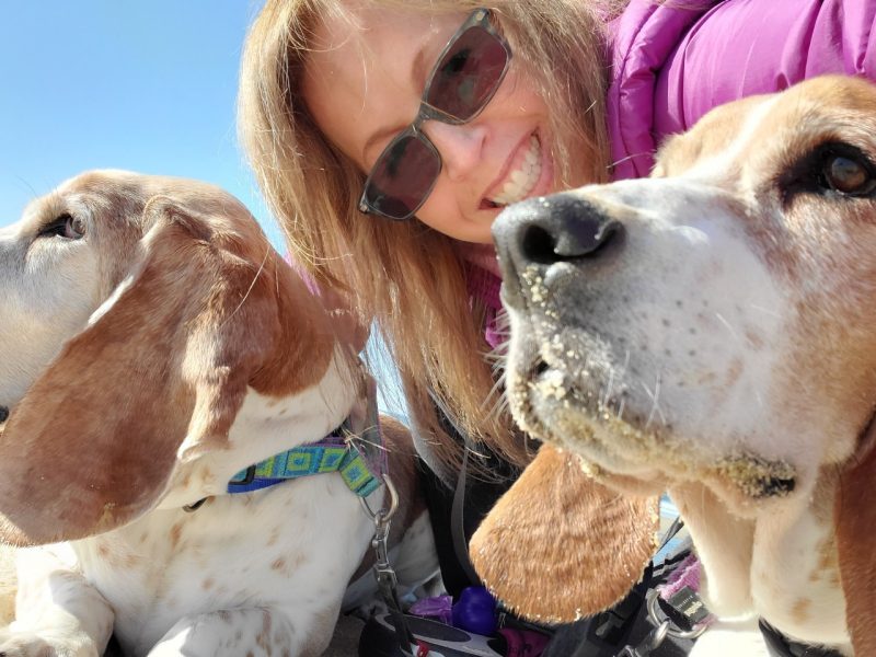 Erin O'Leary posing with her two basset hounds at the beach.