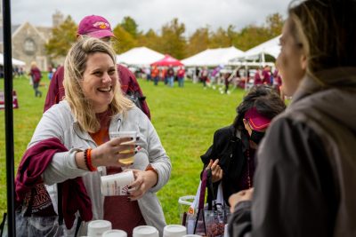 A woman smiles after getting a drink at the Homecoming tailgate