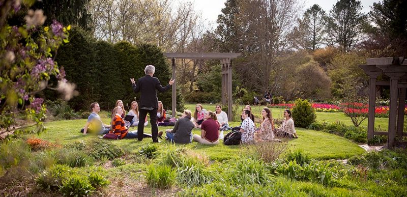 students sitting in a garden with an instructor teaching