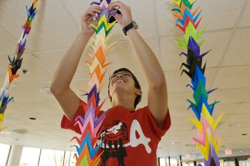 student hanging origami cranes stringed together