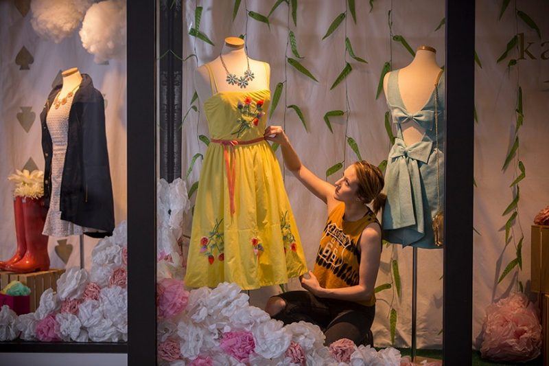 student adjusting clothes on manakin in apparel window display
