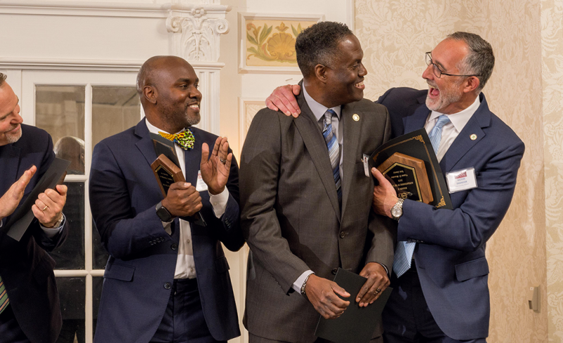 dr. clemons is named 2023 virginia superintendent of the year; we see him smiling as he receives his accolades from the presenter and his fellow nominees