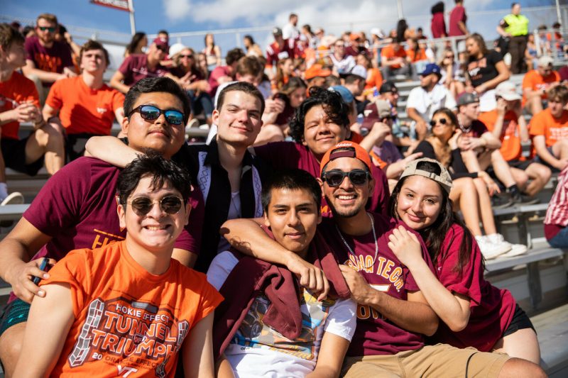 a multi racial group of people enjoying each other's presence at a VT football game