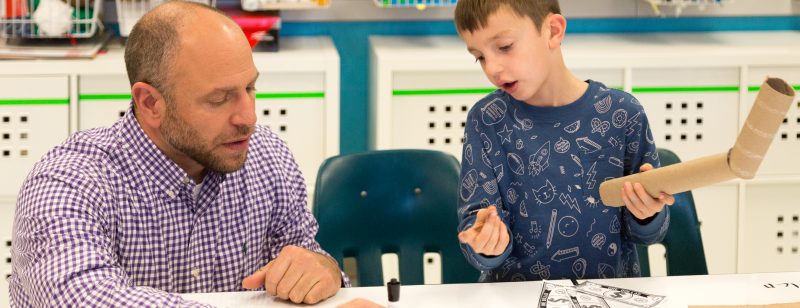 a white male teacher works with a student in an elementary classroom thinkabit classroom setting