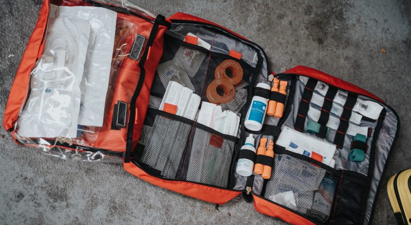 the image shows a blue medium sized first aid kit and a smaller, red first aid kit. Both are artistically placed in the lower right quadrant of the image