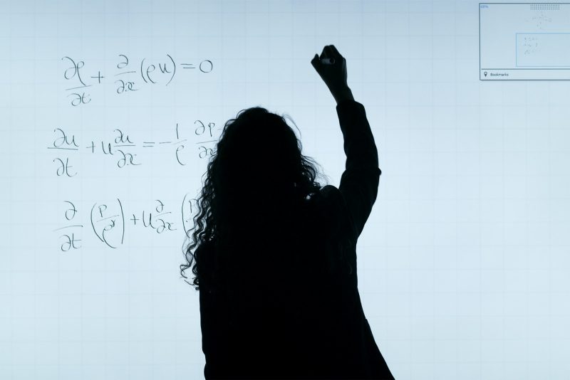 we see the silhouette of a woman solving a partial differential equation that is lit from behind