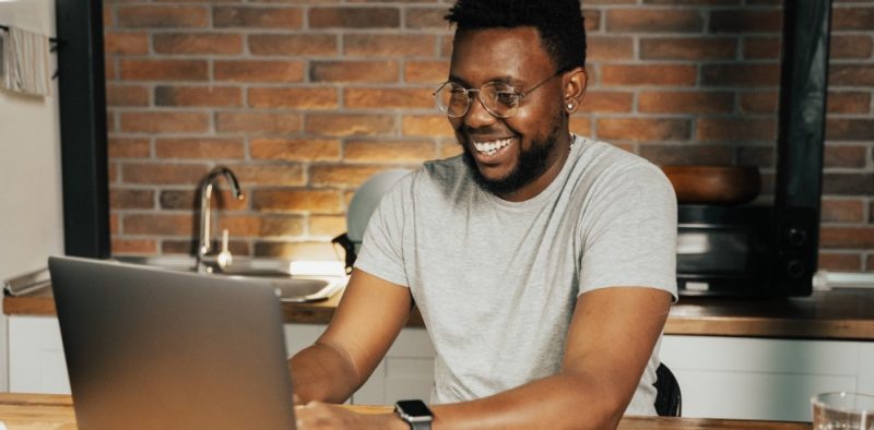 a handsome african american man smiles as he works on his computer