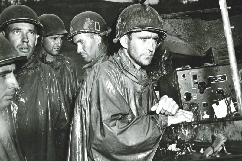 Soldiers in the U.S. Army’s 77th Infantry Division listen to the news of Germany’s surrender on May 8, 1945, thereafter known as Victory in Europe Day. Just minutes after the photograph was taken, the men were back at their posts, a few yards behind the frontlines of continued fighting in Okinawa, Japan.
