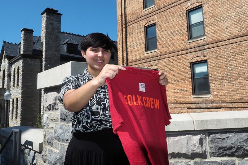 Melissa Velez Nazario holds her t-shirt from the Smithsonian Folklife Festival, where she completed an internship for her Humanities for Public Service major.