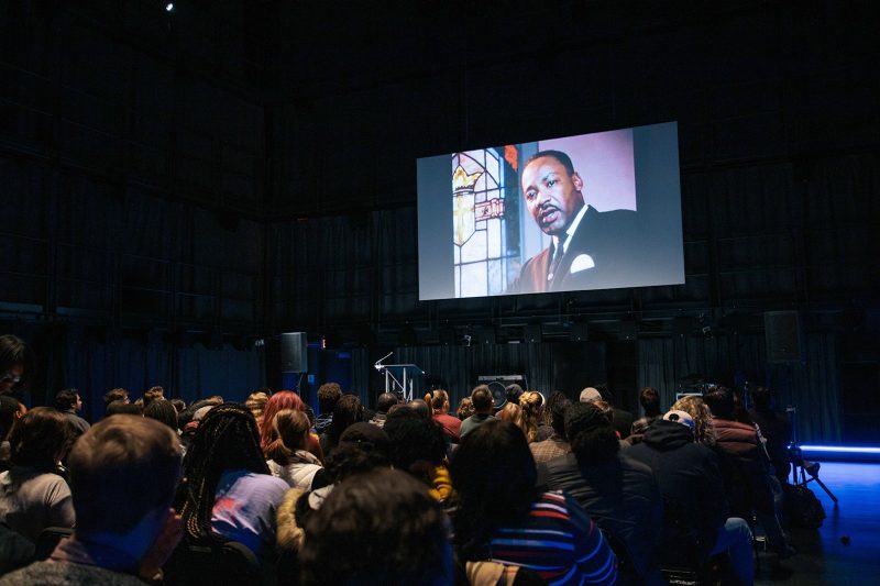 Attendees of the 2019 Rev. Dr. Martin Luther King Jr. Arts and Oration Competition watch footage during the event.