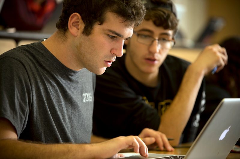 Two male students gaze at a laptop screen