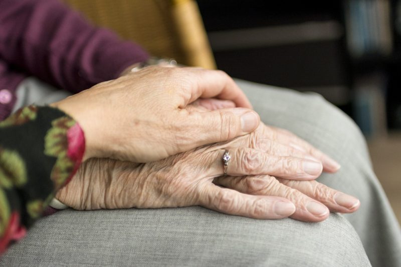 A woman's hand rests upon an older woman's hands