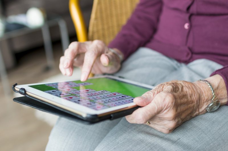 Elderly woman playing solitaire on a tablet