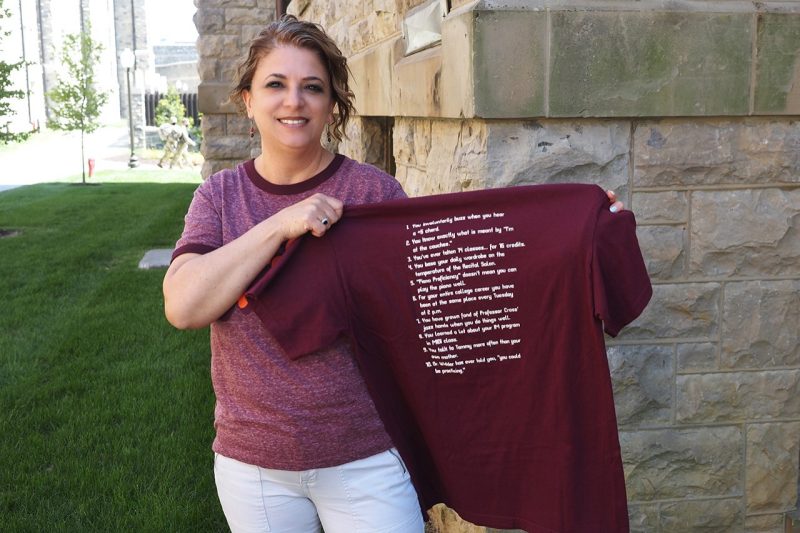 Tammy Henderson holds up a maroon t-shirt with white lettering.