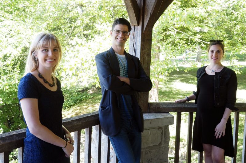 Group photo of the three guest editors standing in a gazebo surrounded by greenery