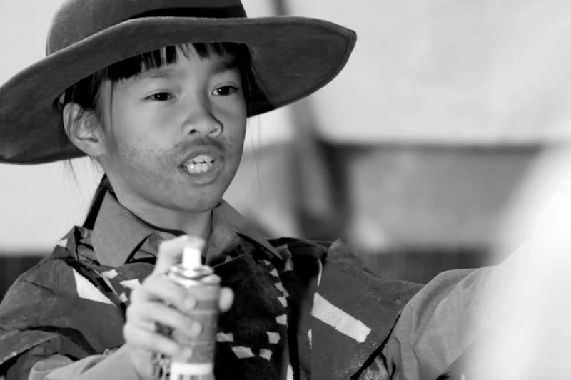 Black and white picture of Hadley dressed as a cowboy, holding a can of Silly String.