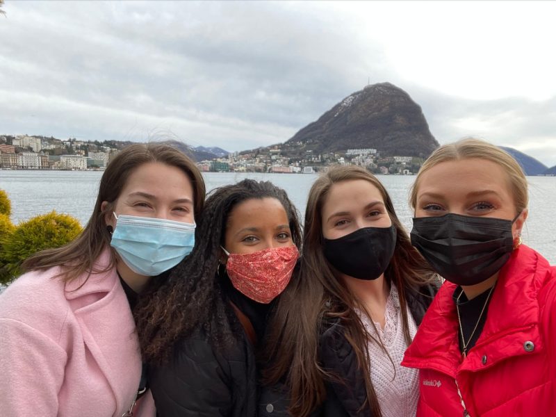 Four students in front of Lake Lugano in Switzerland.