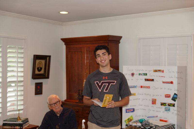 Vince Vasudevan shortly after learning he’d been accepted to Virginia Tech as a Beyond Boundaries Scholar recipient. Vasudevan stands in front of a white board offering congratulations while holding a congratulatory card and standing next to a family member.