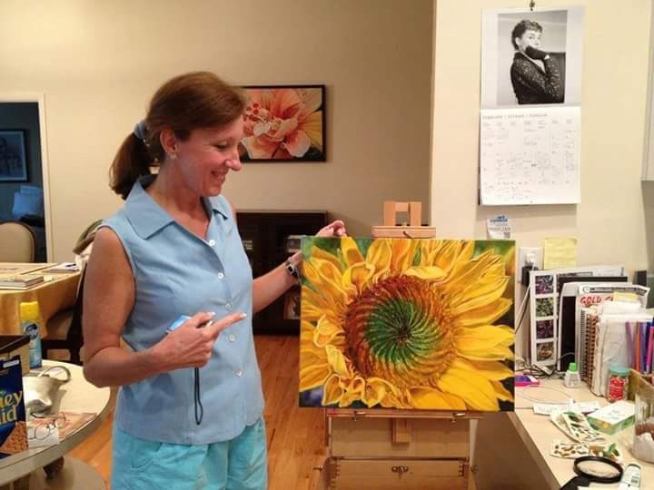 Rebecca Ribler showcases one of her paintings of a sunflower inside the family home.