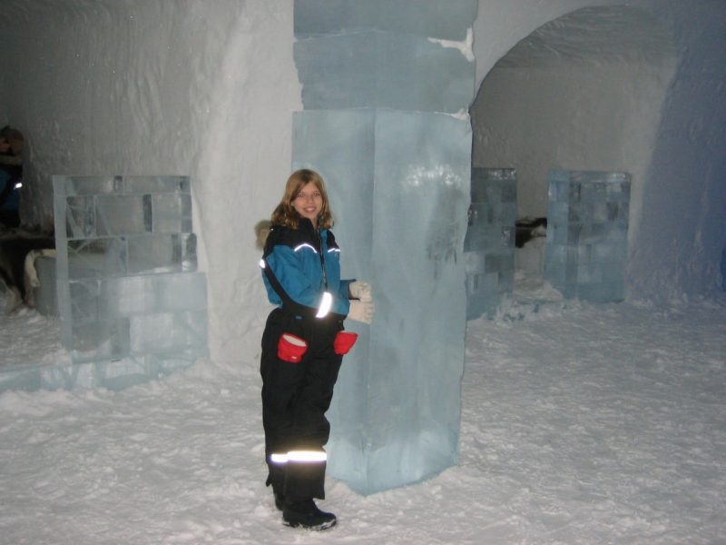 Savannah Mandel stands in an ice hotel in Sweden next to a column made of ice