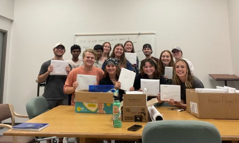 Photo of the Alpha Phi Omega fraternity participating in a book wrapping party on campus in 2022. 