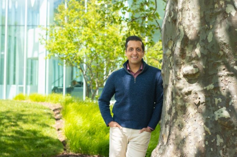 Rishi Jaitly, professor of practice and distinguished fellow in the Center for Humanities is photographed standing against a tree on VT campus