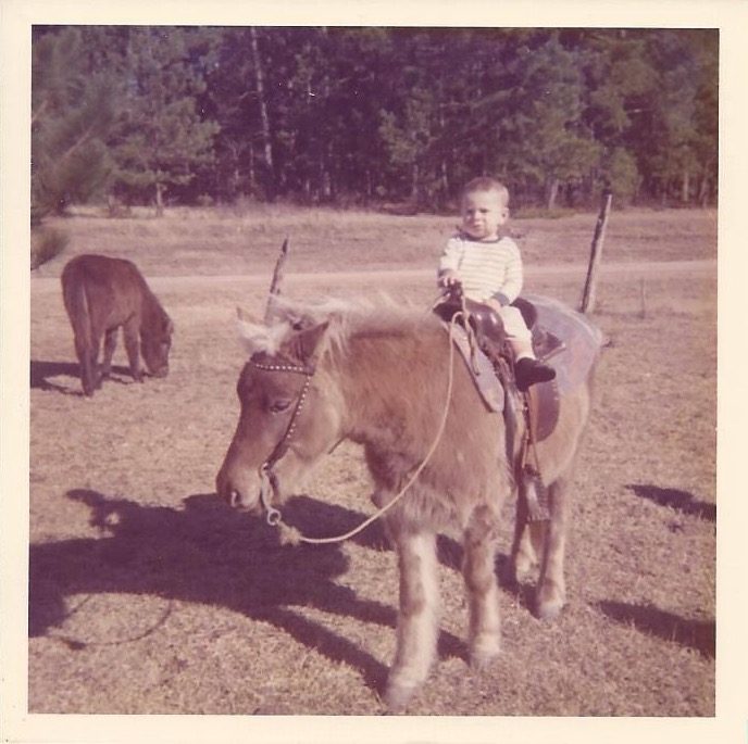in this sepia-tinted image, we see Dr. Charles Lowery as a small boy, sitting comfortably in a saddle on a shaggy pony's back