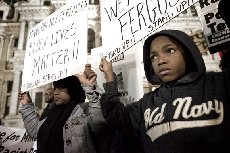 A young protester and his mother holding signs at a Black Lives Matter protest at Philadelphia City Hall in November 2014.