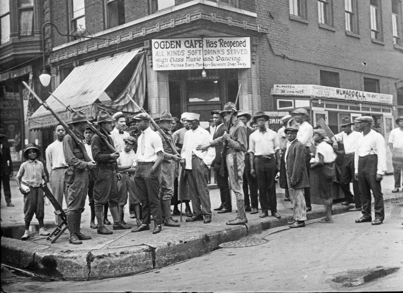 A group of citizens and armed members of the National Guard stand in front of the Ogden Cafe during the race riots in Chicago, Illinois, in 1919.