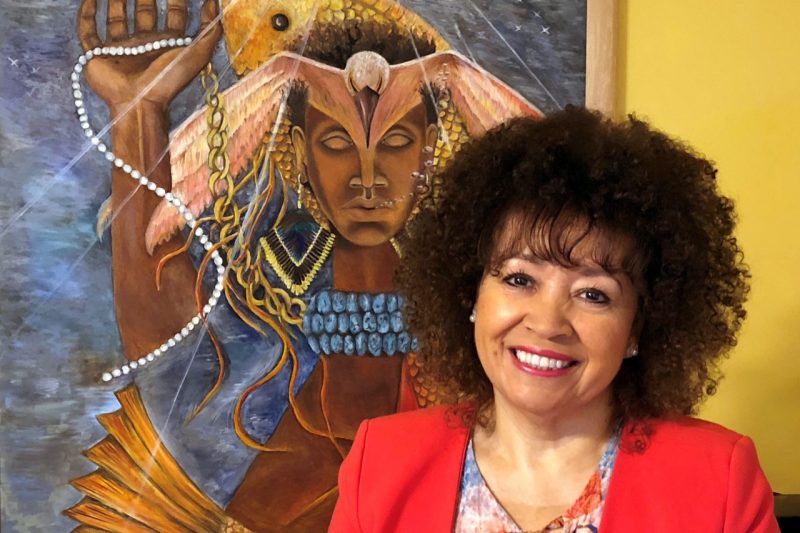 Lucinda Roy stands in front of “Suffering the Sea-Change: Not Venus But Rising,” a painting she created for her Middle Passage Series. Photo courtesy of Lucinda Roy.