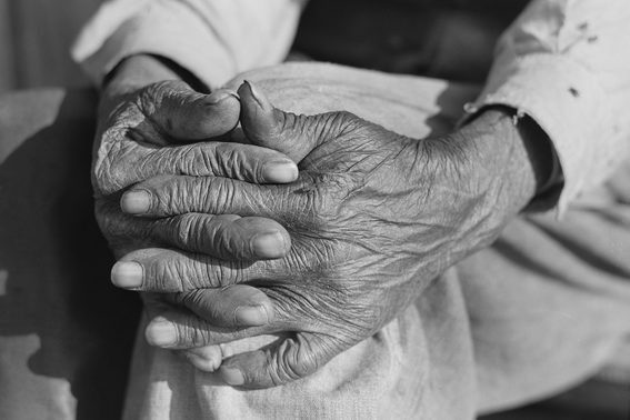Black and white photo of older Black hands clasp together