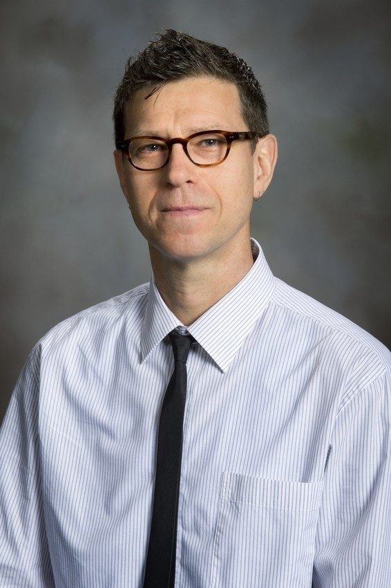color photo of male professor wearing tie and white shirt