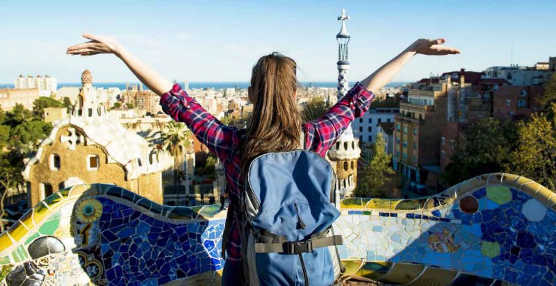Picture of student greeting European urban vista with open arms