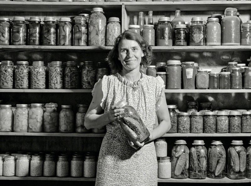 1939 photo of a woman holding home-canned jar of food
