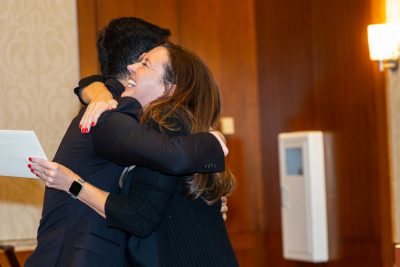 Property management student hugs advisory board member as she awarded him a scholarship.